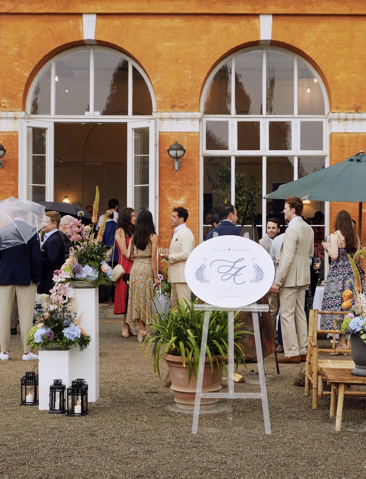 Guests gathering at a wedding welcome reception outside a Danish manor with flowers and lanterns