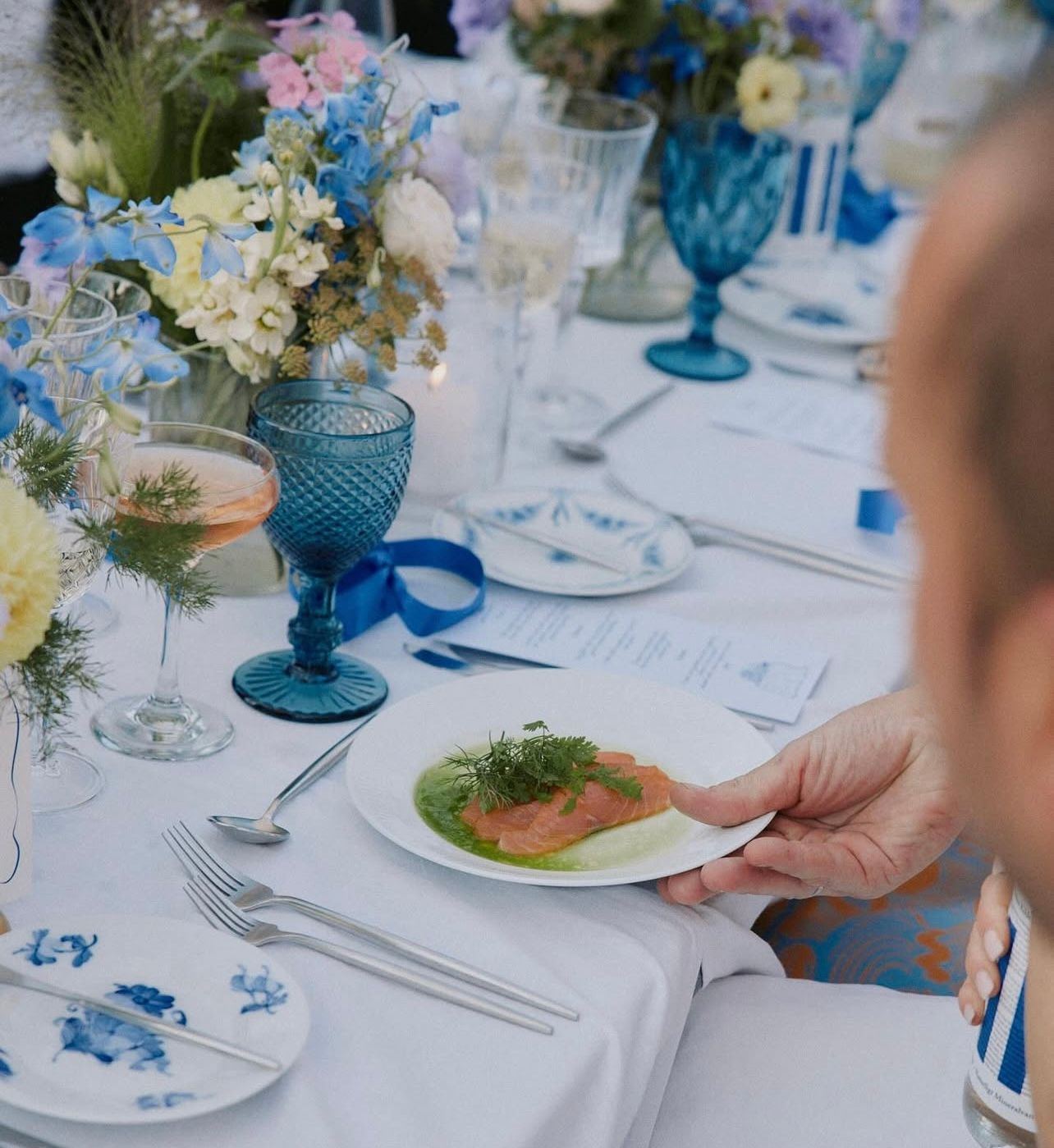 Table details with blue glassware and fresh floral arrangements