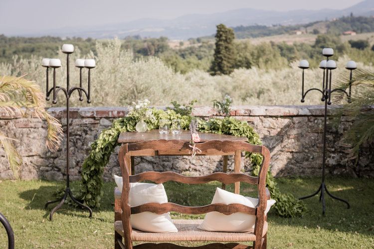 A wedding table set against a Tuscan stone wall with garlands